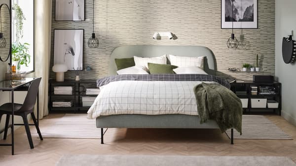 A bedroom with a light green upholstered bed.