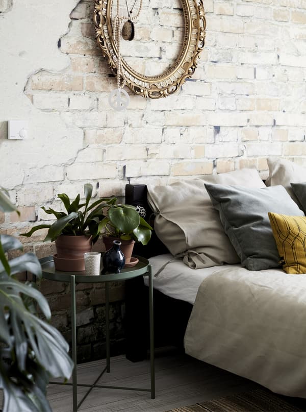 A bedroom with an exposed brick wall and plants.