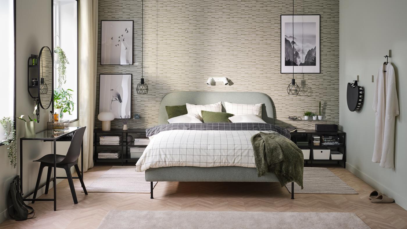 A bedroom with green and black furniture, framed prints and an upholstered bed frame in Gunnared light green.