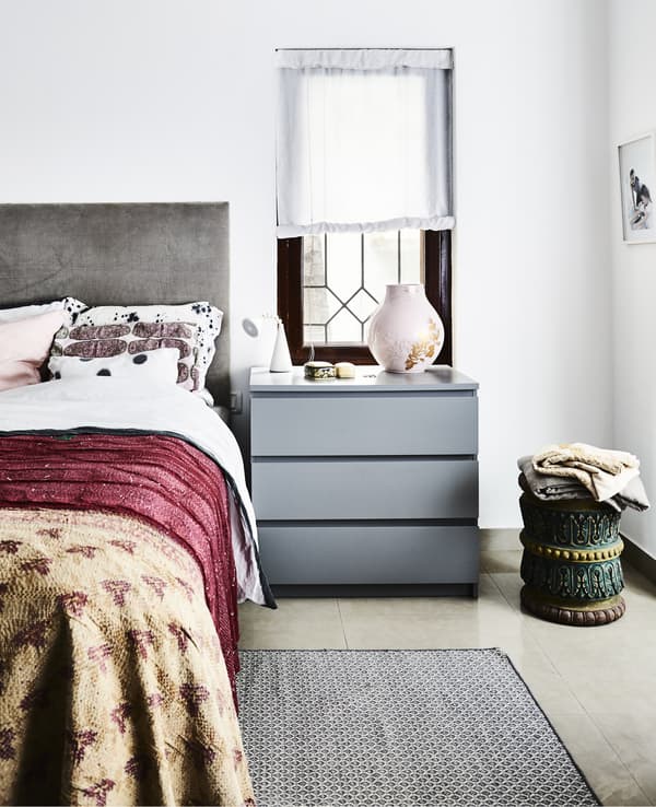 A bedroom with grey furniture and bright textiles.