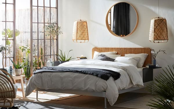 A bedroom with KNIXHULT pendant lighting hanging either side of a bed with bamboo headboard.