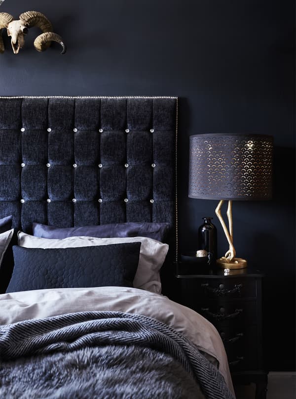 A bedroom with layered bedding and dark walls.