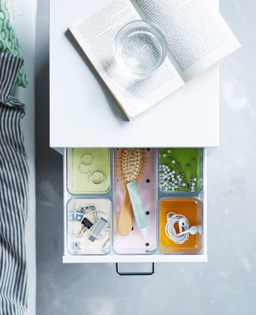 A bedside table drawer that has compartments in it to organize different items