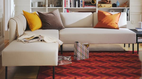A beige LILLEHEM sofa in the living room with a red rug on the floor.