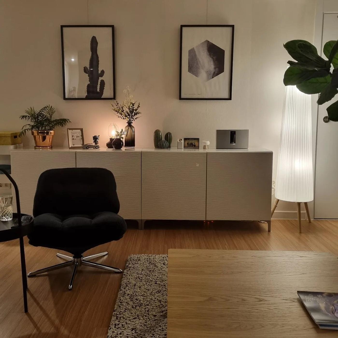 A BESTÅ storage unit with beige doors and lots of home accessories in the living room.