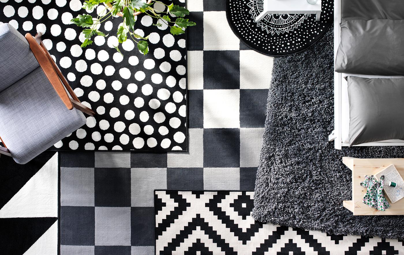 A bird’s-eye view of layered black and white rugs in different textures and patterns on the floor of a living room.