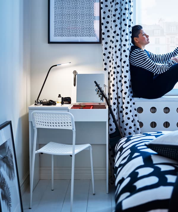 A black and white polka dot bedroom scheme, plus a white desk, chair and painted floor, with a woman sitting in the window.