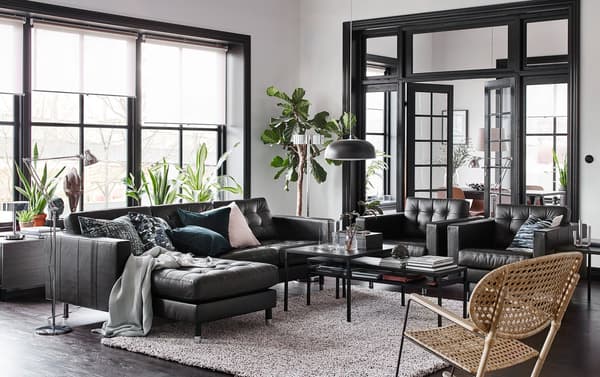 A black, beige and white living room with a IKEA LANDSKRONA black leather sofa with chaise lounges and two armchairs.