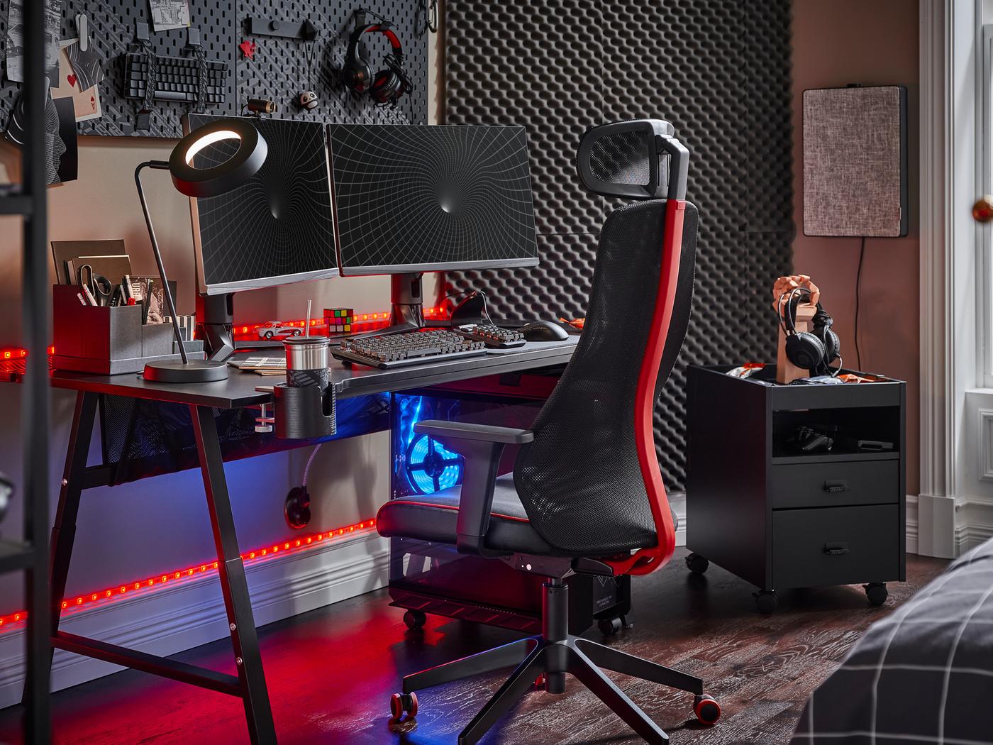 A black UTESPELARE gaming desk with two screens, a black gaming chair, a black drawer unit and various gaming accessories.