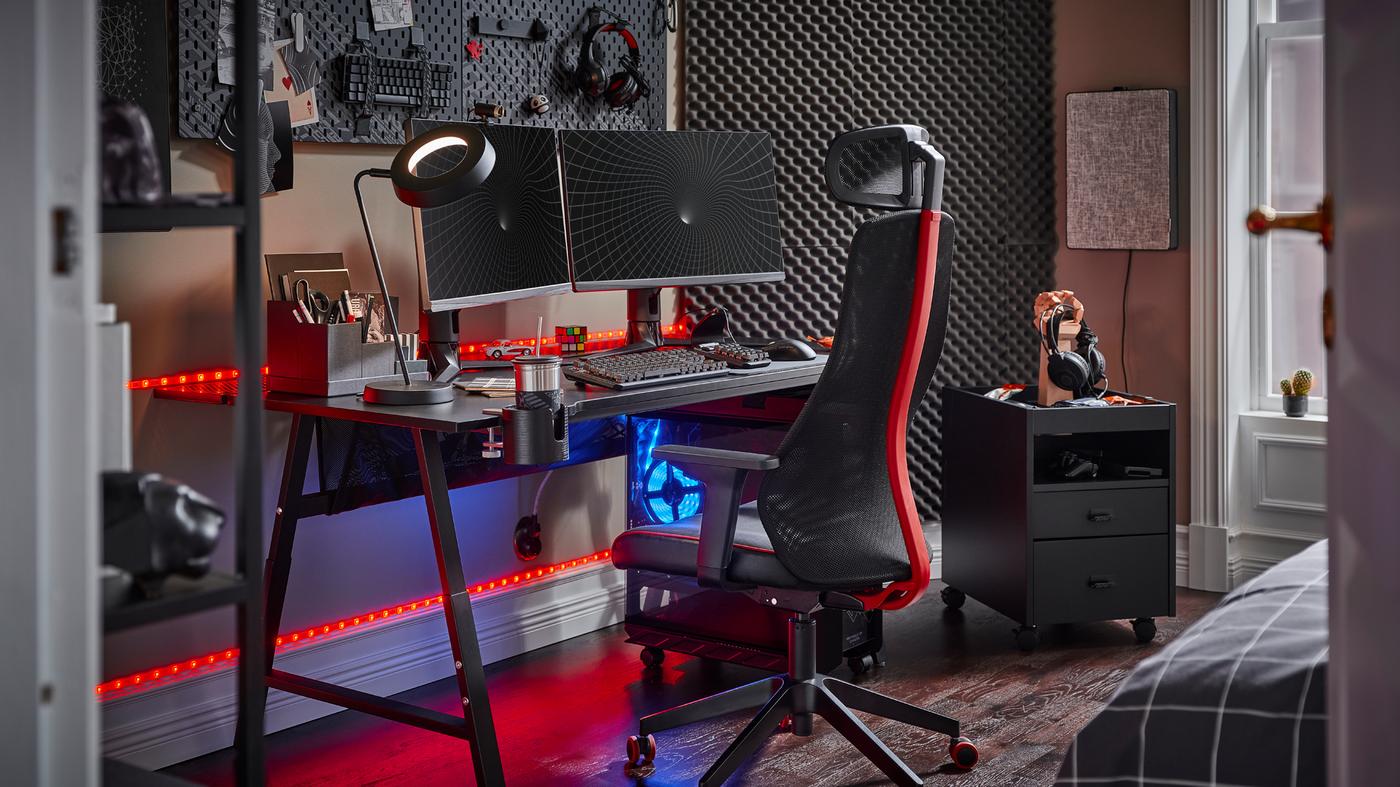 A black UTESPELARE gaming desk with two screens, a black gaming chair, a black drawer unit and various gaming accessories.