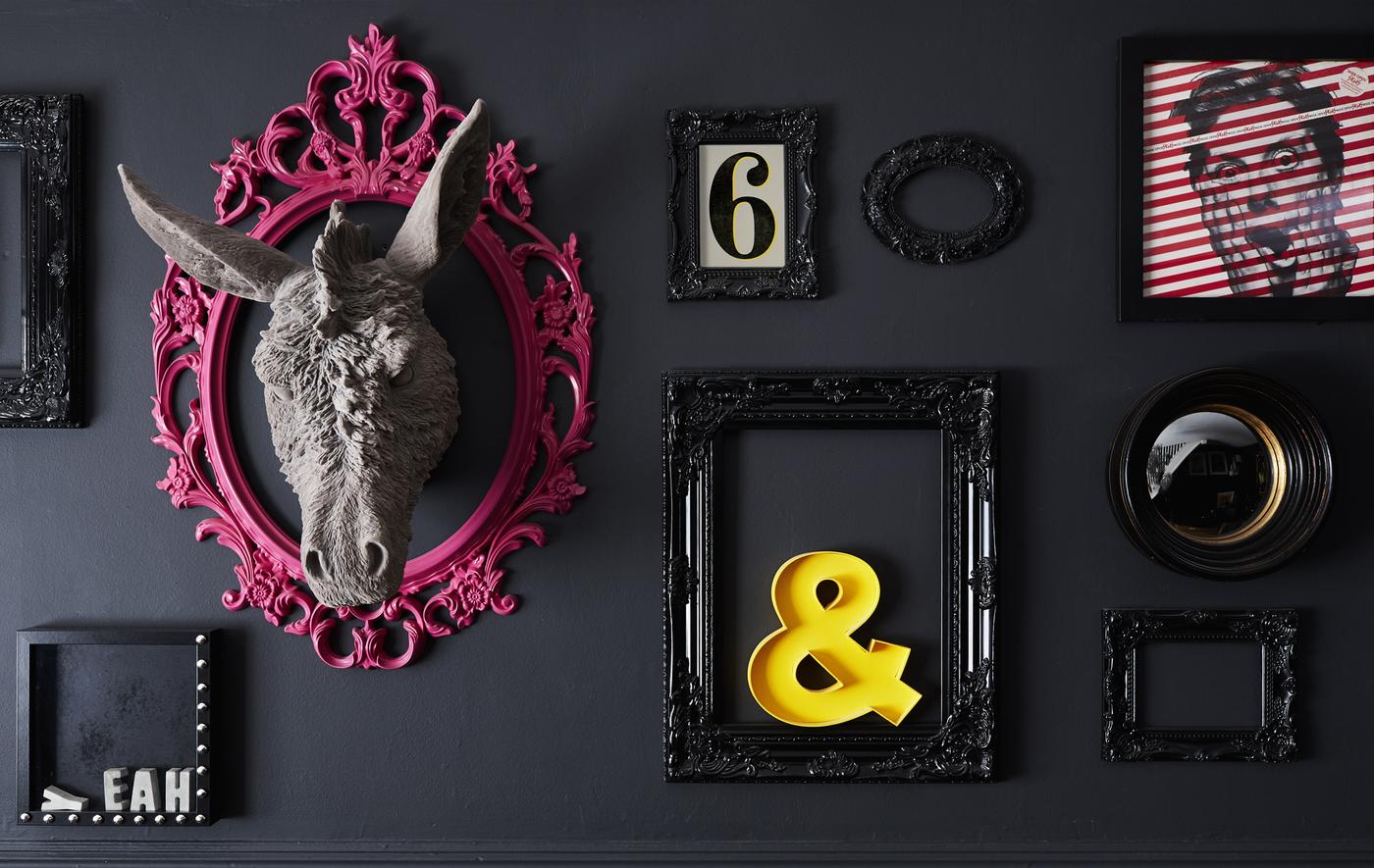A black wall decorated with different frames and objects.