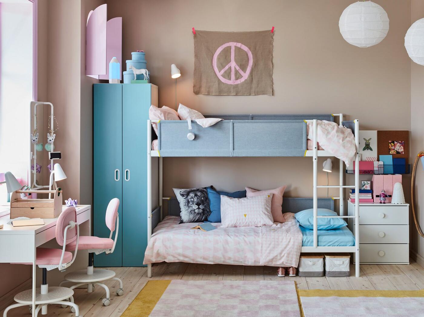 A blue and pink children's room for siblings with a white bunk bed, a white shared desk and light pink desk chairs.