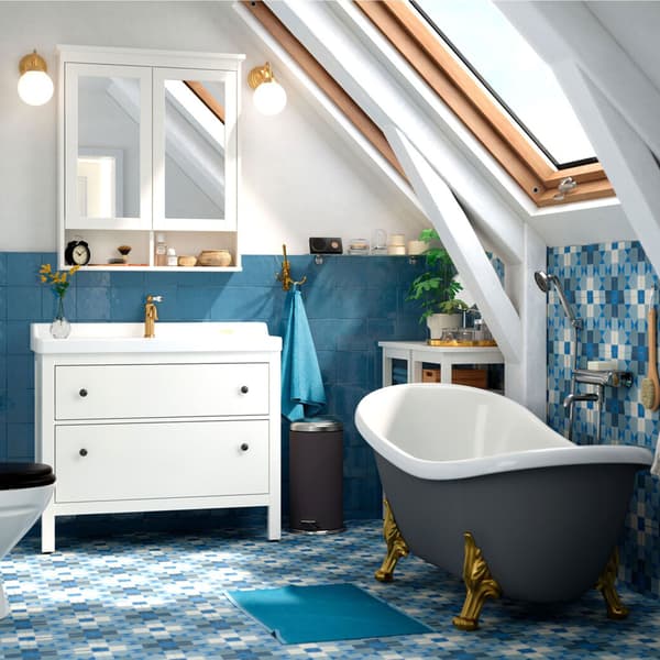 A blue bathroom with grey bath tub, a sloping ceiling and an IKEA HEMNES/RÄTTVIKEN wash-stand and mirrored wall unit.