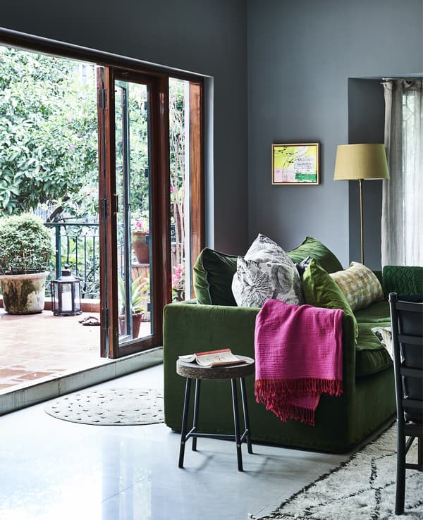 A blue living room with brightly coloured textiles.