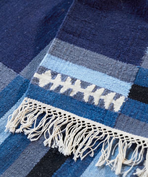 A blue patterned rug with fringed edging.