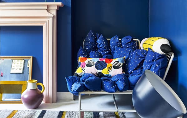 A blue sofa against blue walls and pink fireplace.
