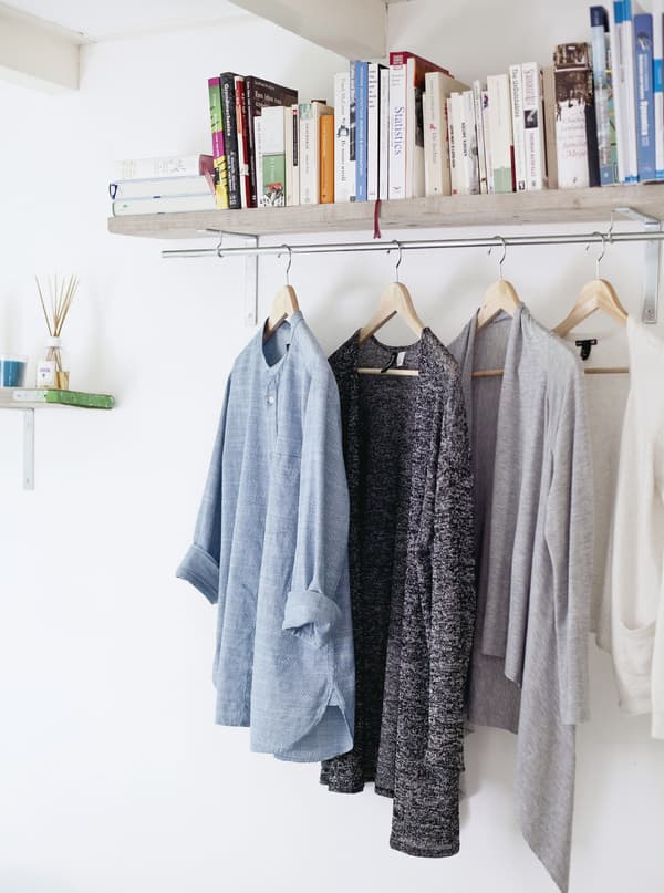 A book shelf with a hanger below holding clothes.