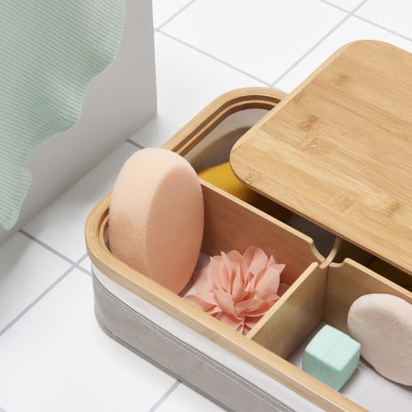 A box with a lid partially removed showing compartments containing small sponges and accessories.