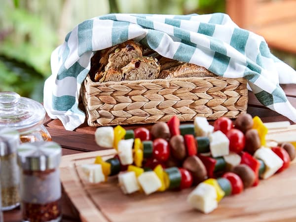 A bread basket and skewers of food for the barbeque.