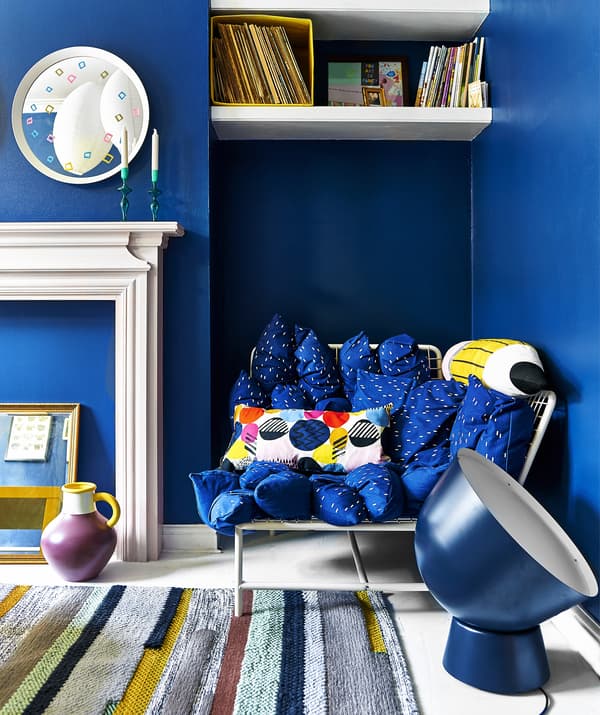 A bright blue living room with sofa, oversized lighting and rug.