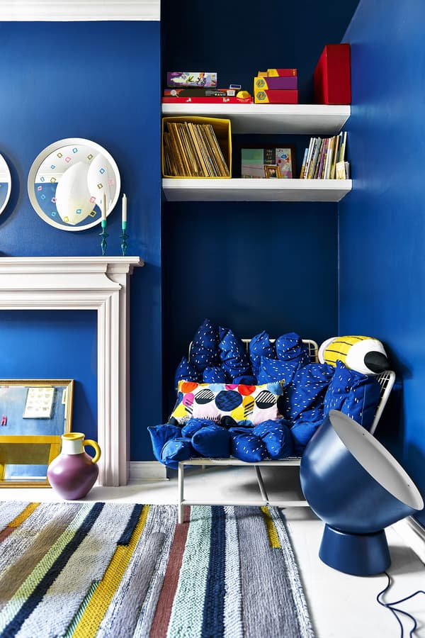 A bright blue living room with sofa, oversized lighting and rug.