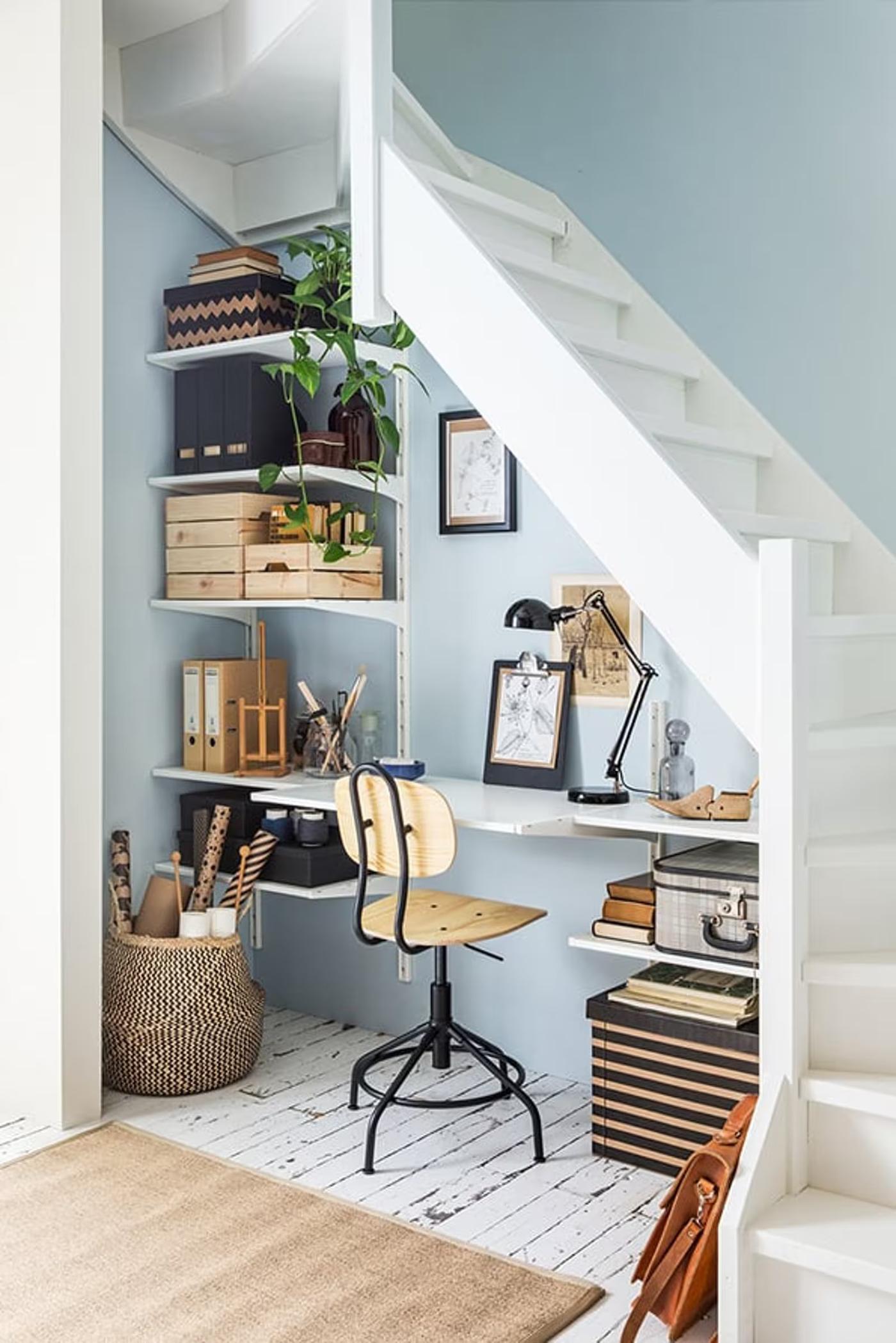 A bright living room with a workspace under the stairs.