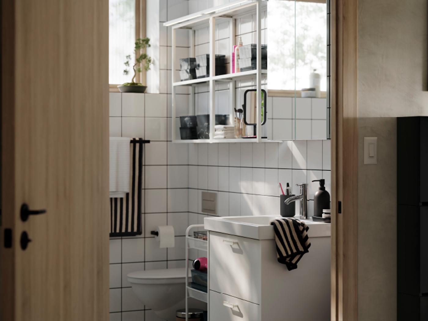 A bright, modern-style bathroom with white HAVBÄCK/ORRSJÖN storage, ENHET wall shelves with frames and striped towels.