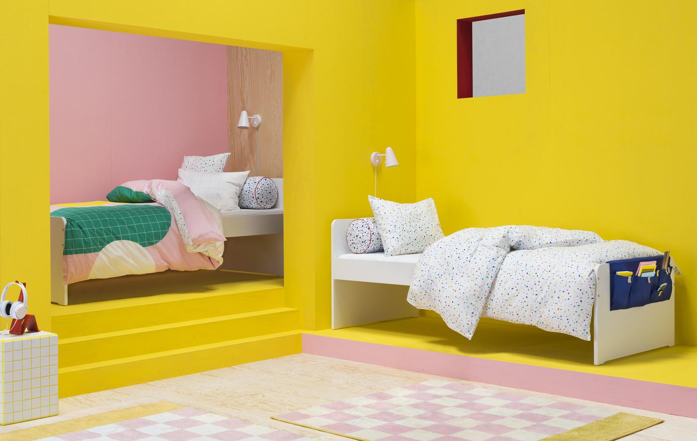 A bright pink and yellow bedroom with two single beds with colourful, graphic duvet covers.