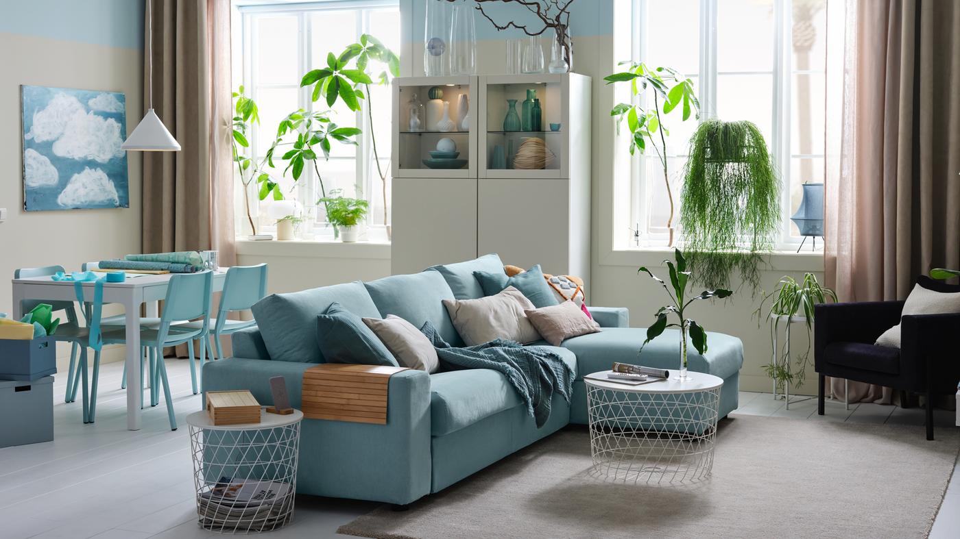 A bright studio with a 3-seat sofa-bed with chaise longue, a white storage combination and a dining area.