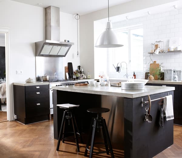 A bright, white and black modern kitchen with island, bar stools, and open storage.