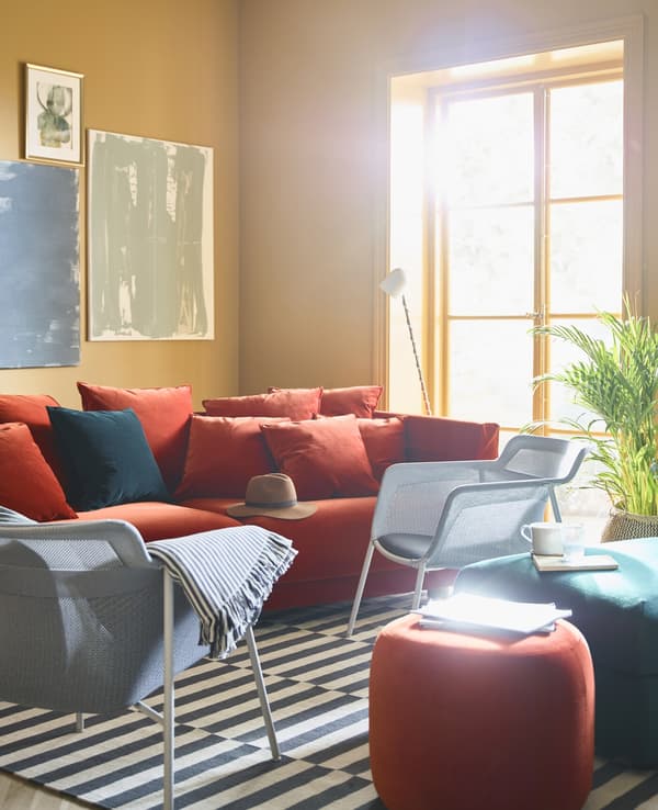 A brightly colored living room with ochre walls is burnished with a red sofa and armchairs.