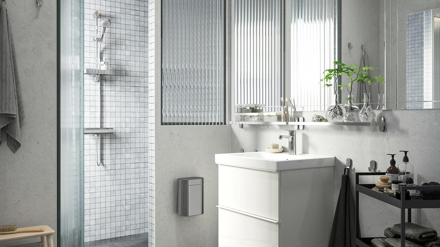 A brightly lit bathroom with a GODMORGON wash-stand, shower with light grey tiles and BROGRUND shower set.