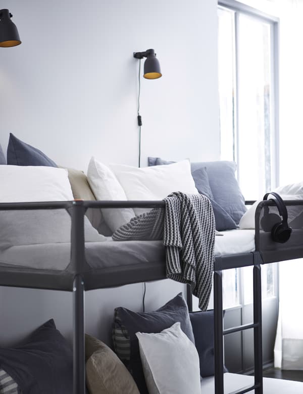 A bunk bed in a living room with gray and white pillows.