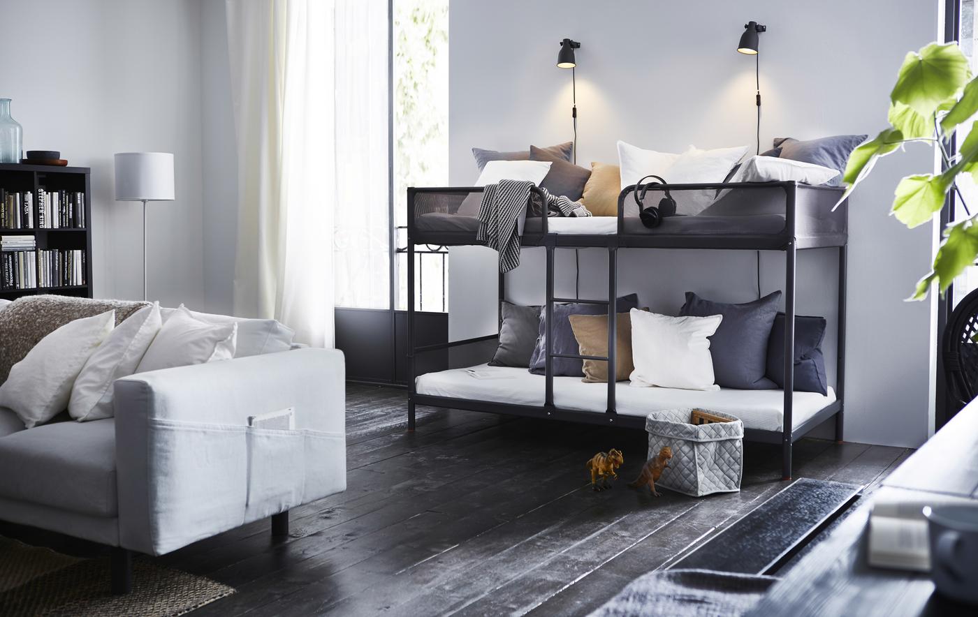 A bunk bed in a living room with gray and white pillows.
