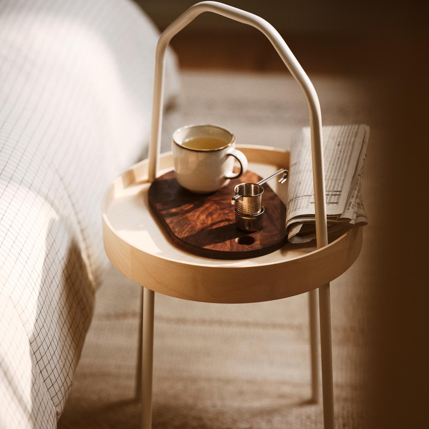 A BURVIK side table with a grey GLADELIG mug set on a KRÖSAMOS chopping board. The side table is on a BRÖNDEN low pile rug.