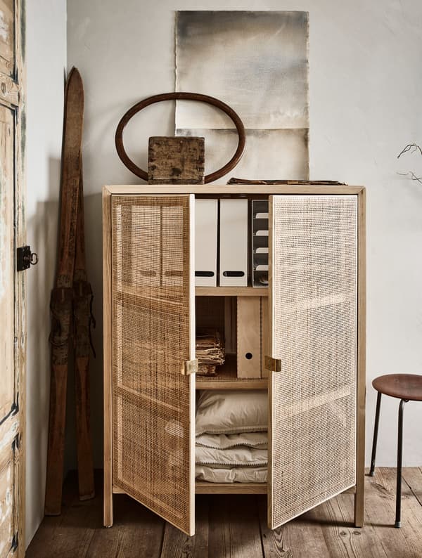 A cabinet holding magazine files and extra bed linen.
