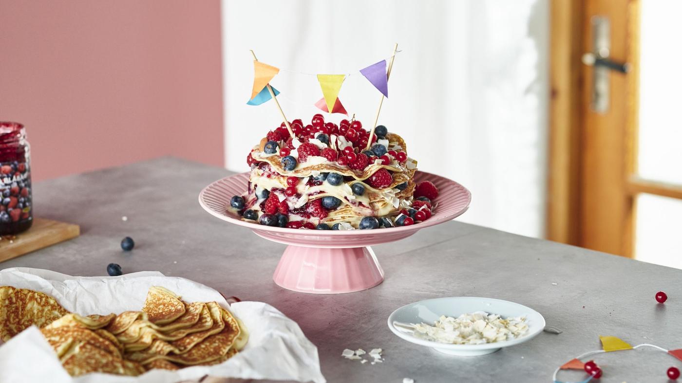 A cake on a pink pedistal with celebration flags coming out of it