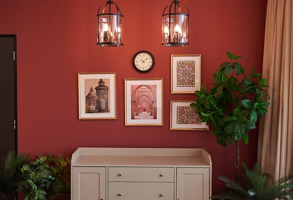 A chest of drawer with frames and a clock hung on top.