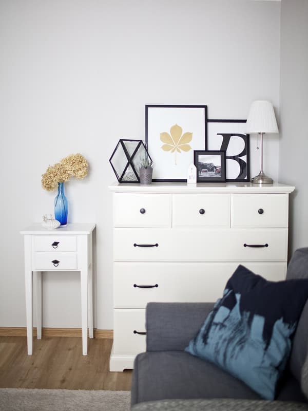 A chest of drawers with picture frames on top.