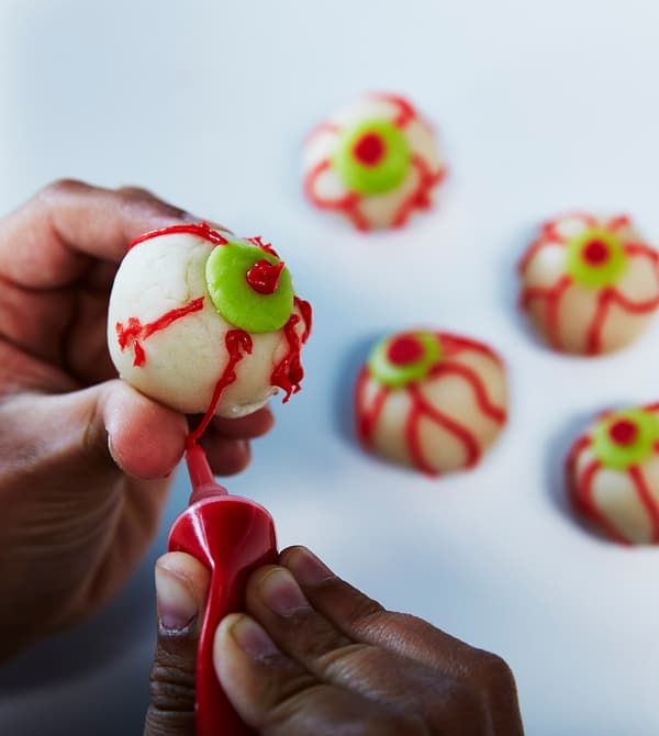 A child decorates eyeball treats.