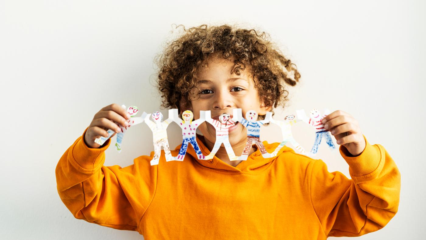 A child in an orange sweatshirt with a decorated and playful garland that illustrates children holding hands.