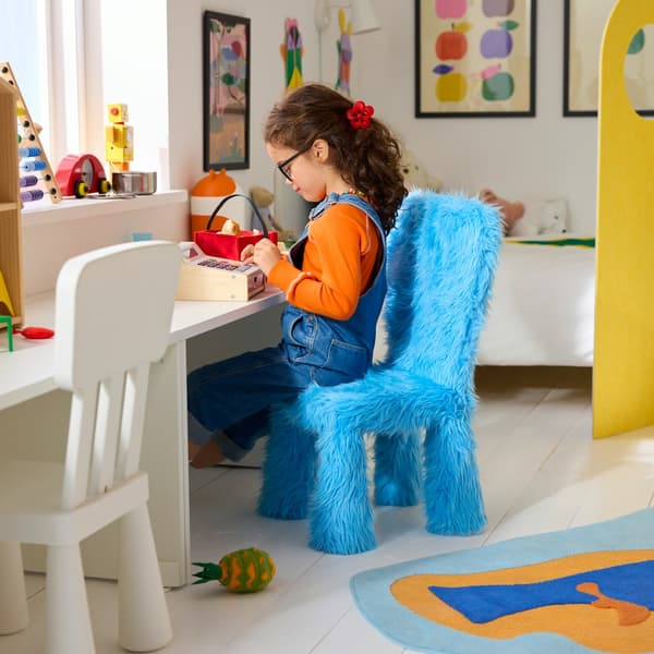A child is sitting on a chair in blue GREJSIMOJS faux-fur cover.