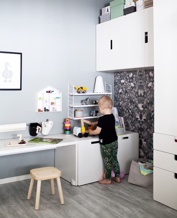A child playing in a neutral colour-schemed bedroom with white furniture.