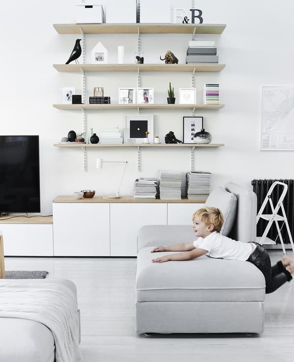 A child playing on top of a modular sofa unit in an open-plan living room with a monochrome coloured scheme.