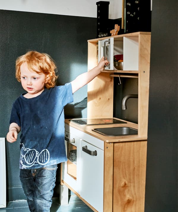 A child playing with a toy kitchen.