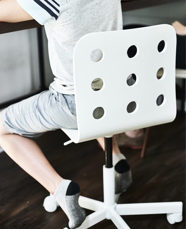 A child sitting on a white desk chair.