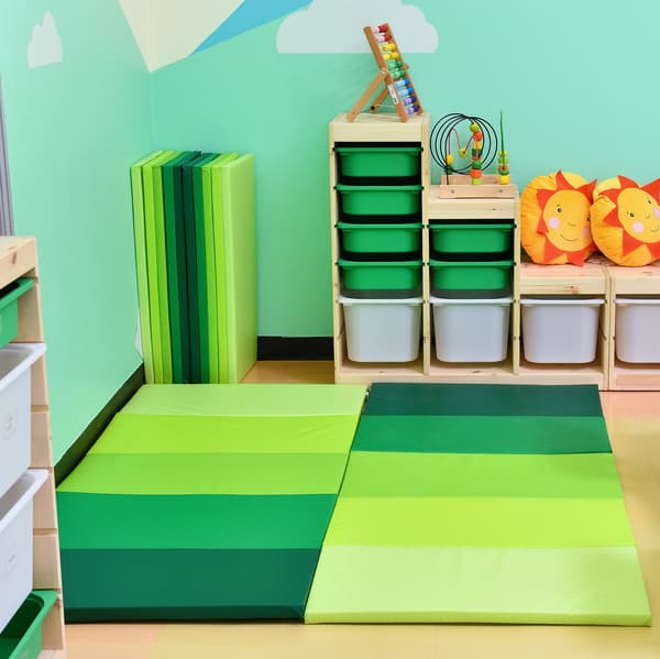 A children play area featuring playmats of different shades of green placed on the floor.