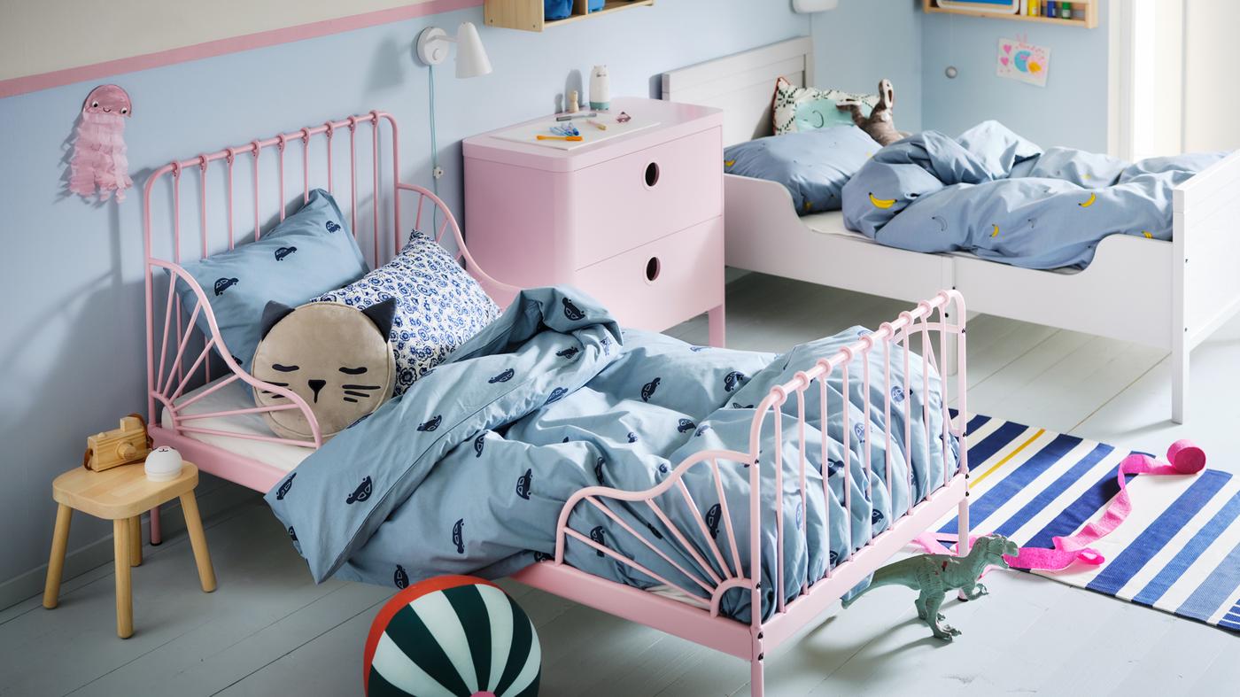 A children's bedroom with a light pink MINNEN extendable bed and a white bed made with blue VÄNKRETS and BARNDRÖM bedding.
