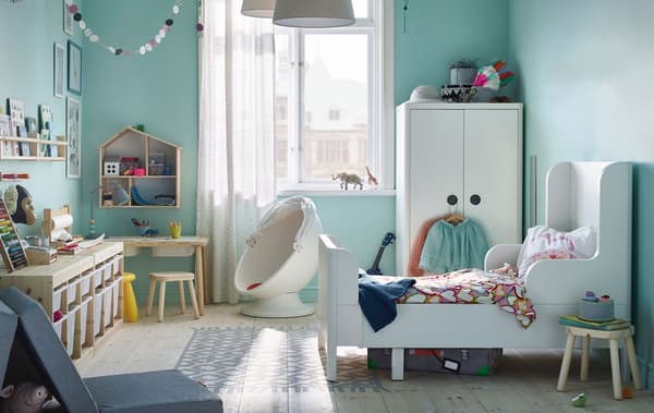 a childrens room with white furniture, TROFAST storage unit and pale blue walls.