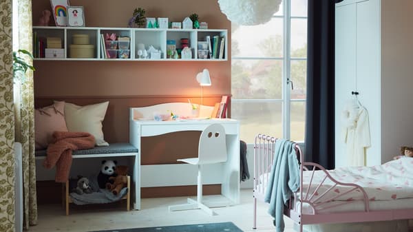 A child's bedroom with a pink bed and white desk.